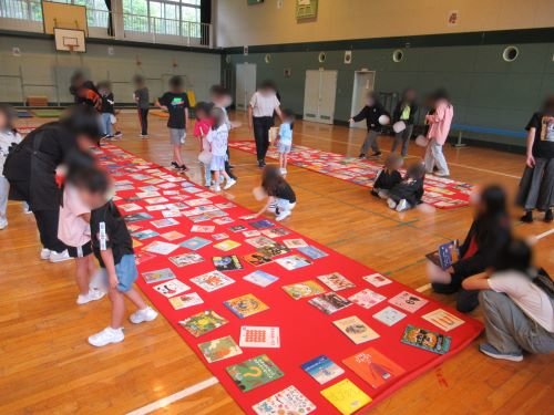 小学生が床に並んだ1000冊の本の中からお気に入りの一冊を探している様子1