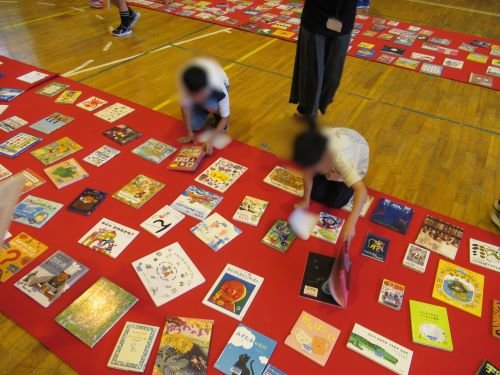 小学生が床に並んだ1000冊の本の中からお気に入りの一冊を探している様子2